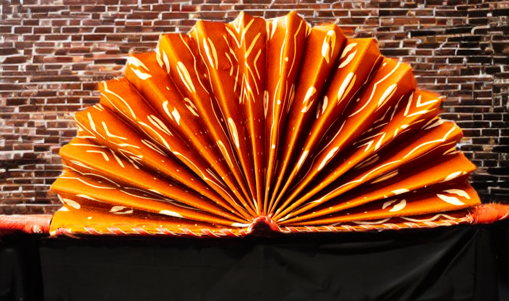 Orange pleated fabric against a brick wall