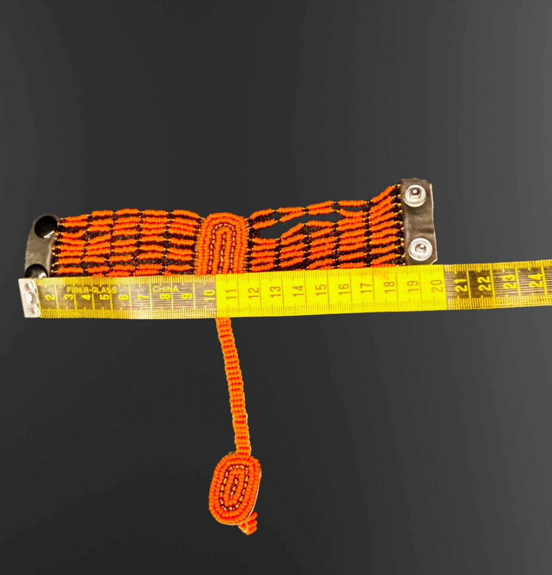 Orange webbing strap with metal clasps on a black background