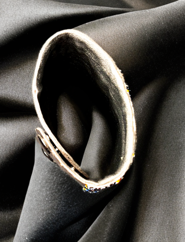 Silver ring with embedded stones on a black fabric background