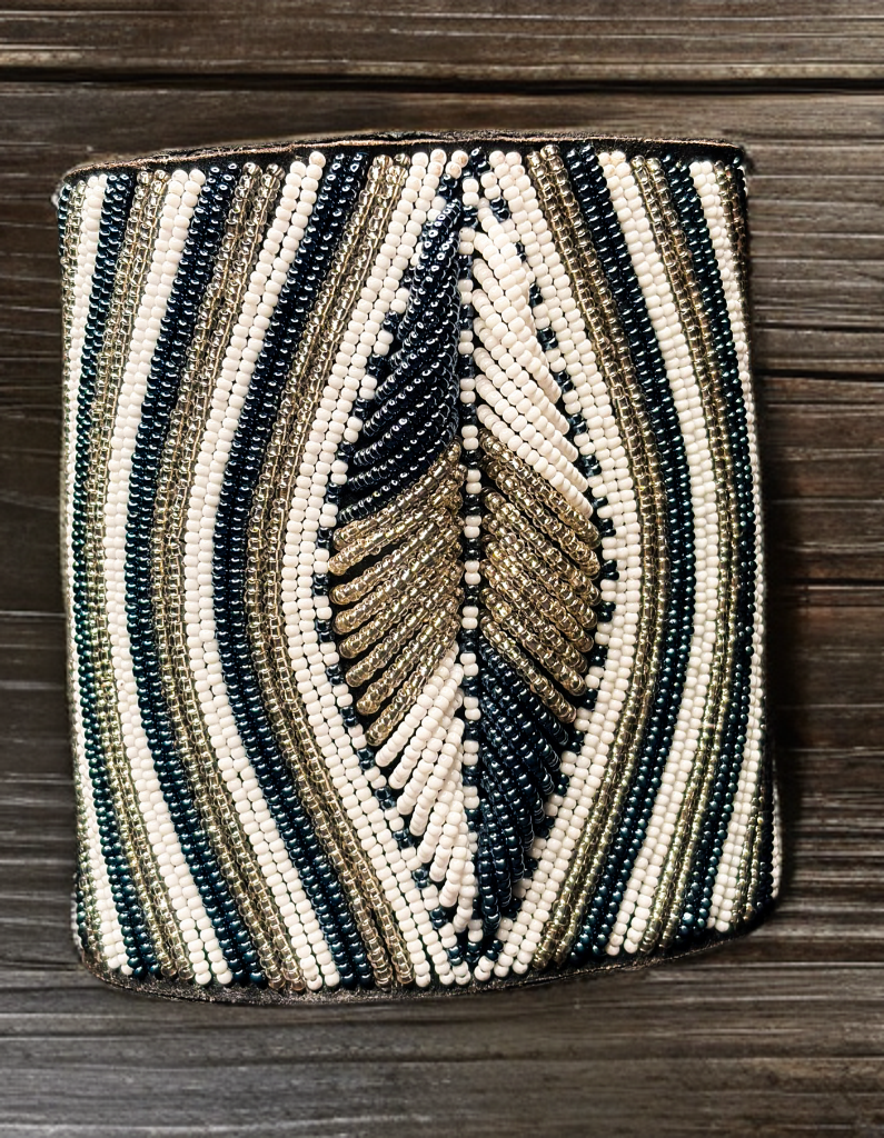 Beaded clutch with black, gold, and beige pattern on a wooden surface