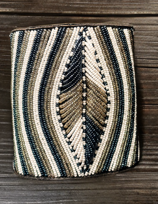 Beaded clutch with black, gold, and beige pattern on a wooden surface