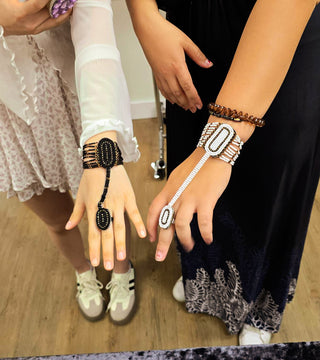 Two people wearing decorative bracelets and rings, standing close together on a wooden floor.